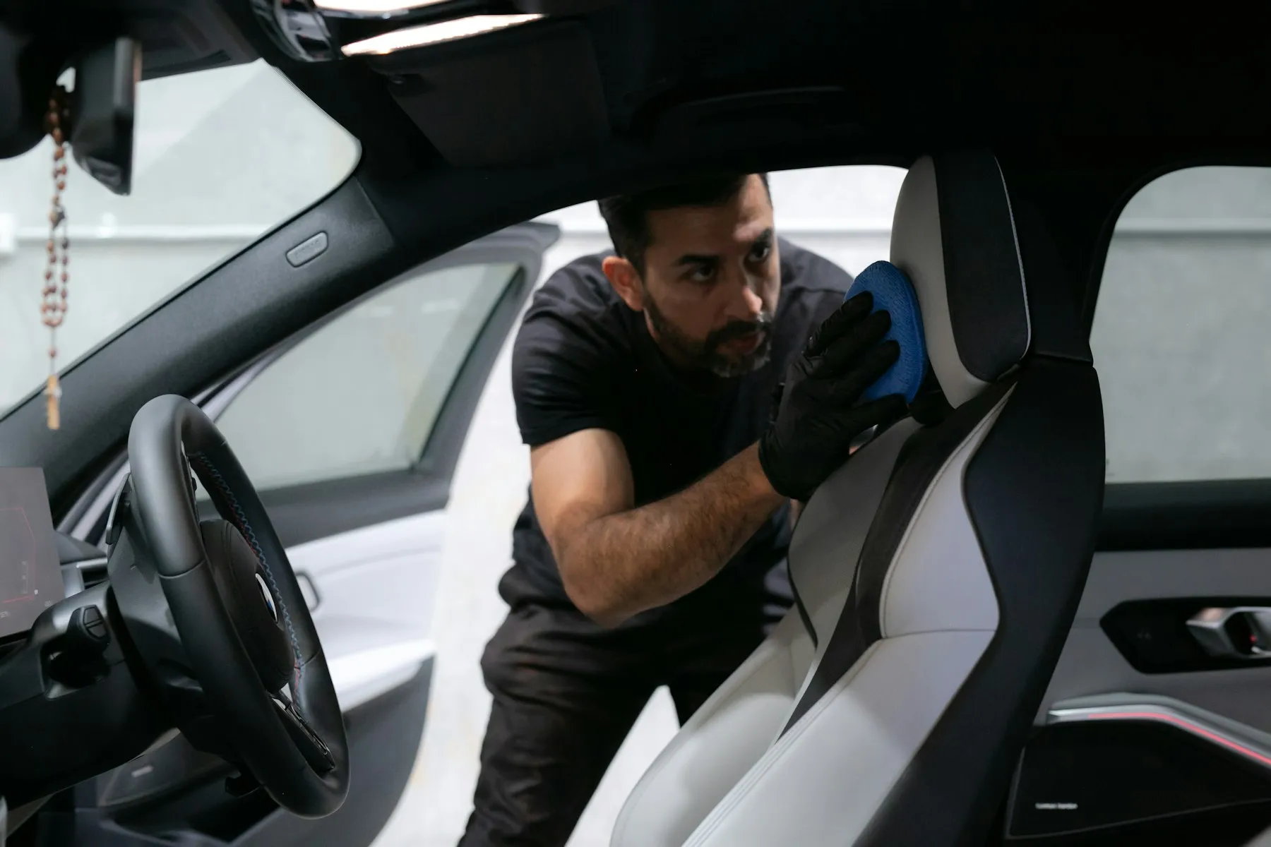 Detailer cleaning a car seat inside the vehicle